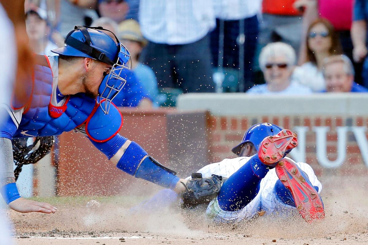 Cubs outfielder Jason Heyward dives in to score as Dodgers catcher Yasmani Grandal drops the ball in the fifth inning.