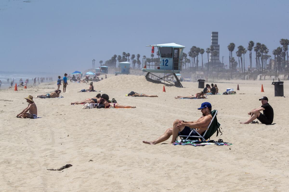 Sunbathers at Huntington Beach on Sunday flout Gov. Newsom's active-use-only order.