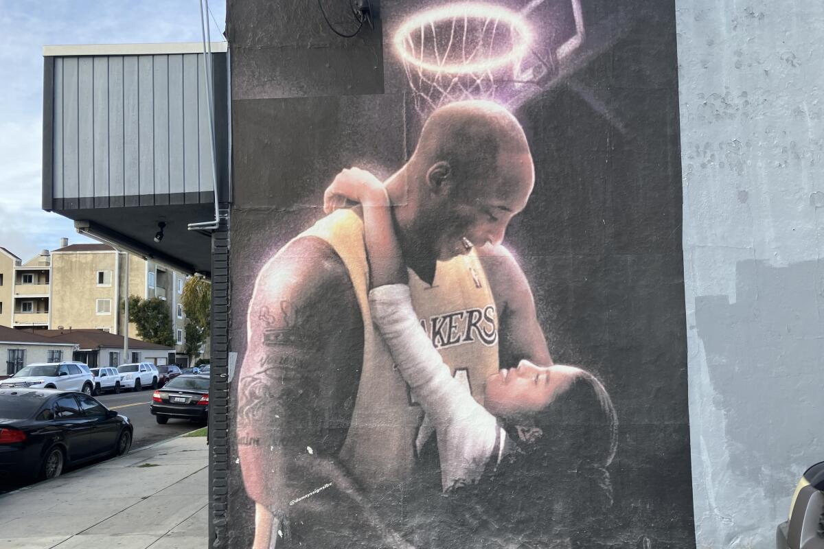 A mural shows Gianna Bryant looking up at her father Kobe while they hug under a basketball rim that looks like a halo.