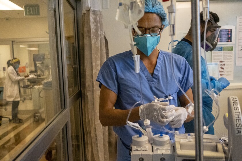 A nurse works with the tubes on an anesthesia machine