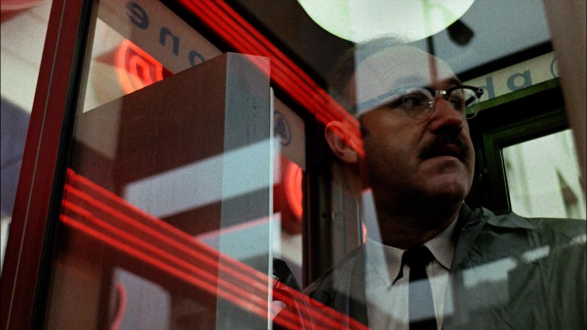 Gene Hackman stands in a phone booth, a look of concern on his face.