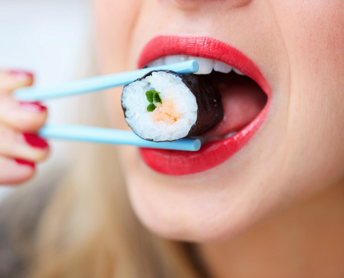 Woman eating sushi with chop sticks , close up.