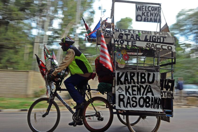 An man on a bicycle pulls a trailer with messages welcoming President Obama to Kenya in Nairobi on Thursday.