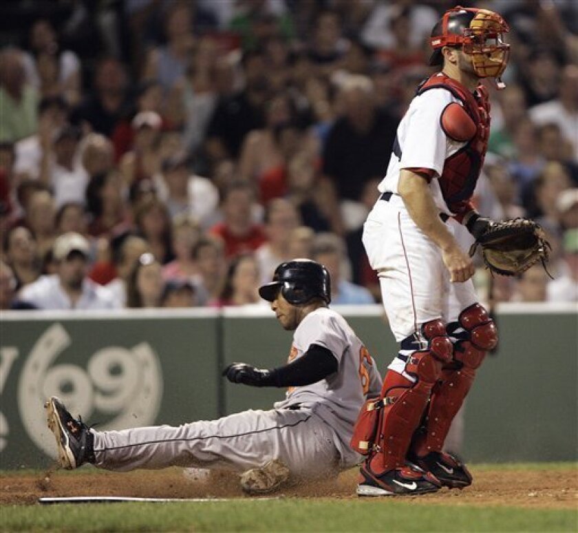 Baltimore Orioles' Melvin Mora, left, slides into home with on teammate Kevin Millar's sacrifice fly as Boston Red Sox catcher Jason Varitek waits for the throw in the seventh inning of a baseball game at Fenway Park in Boston Tuesday, June 10, 2008. (AP Photo/Elise Amendola)