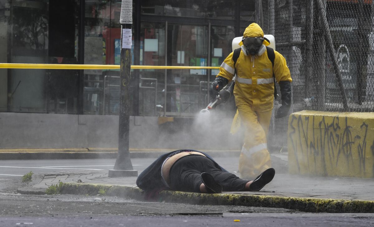 A worker from the forensic department in Quito, Ecuador, sprays disinfectant over the body of a woman who died on the street