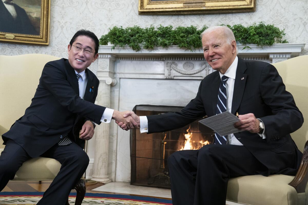 President Biden shakes hands with Japanese Prime Minister Fumio Kishida as they sit in the Oval Office of the White House.