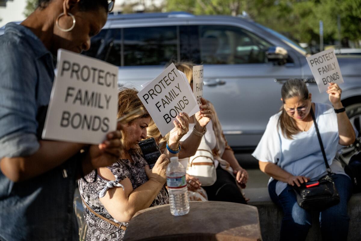 People gather together holding signs that read "Protect family bonds."