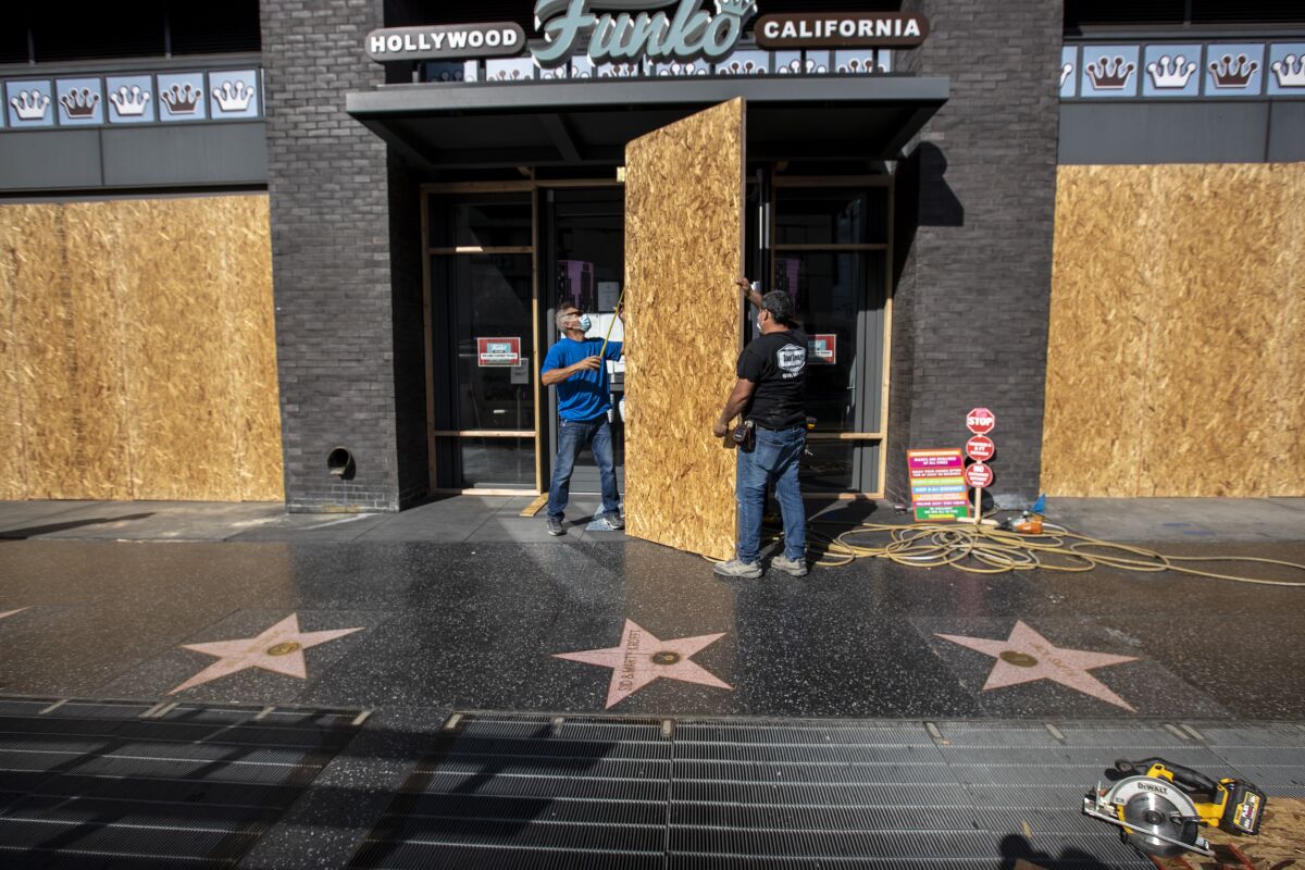 Two men boarding up a storefront on the Hollywood Walk of Fame