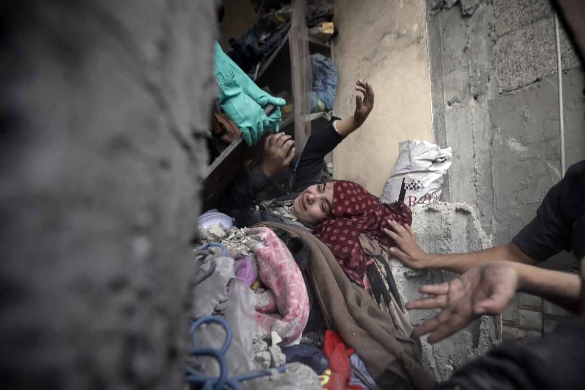 Palestinos tratan de rescatar a una mujer atrapada bajo los escombros de un edificio destruido por los ataques 