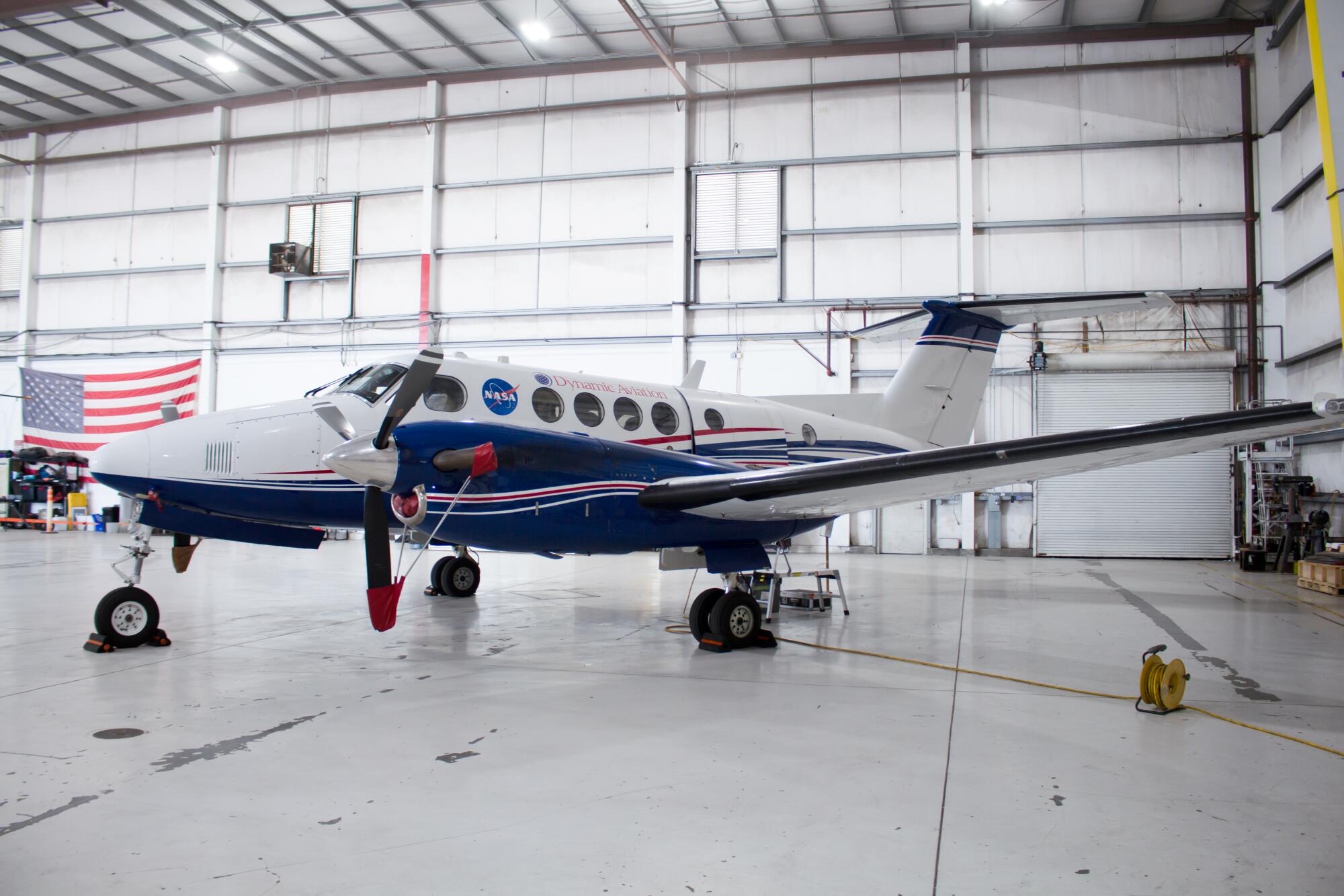 A twin-propeller King Air plane in a hangar.