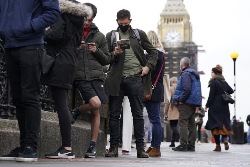 People queue on Westminster Bridge for booster jabs at St Thomas' Hospital, London, Monday, Dec. 13, 2021. Britain faces a "tidal wave" of infections from the omicron coronavirus variant and British Prime Minister Boris Johnson has announced a huge increase in booster vaccinations to strengthen defenses against it. (Kirsty O'Connor/PA via AP)