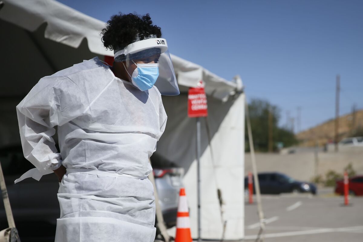 FILE - In this Oct. 26,2020, file photo, a medical worker stands at a COVID-19 state drive-thru testing site at UTEP, in El Paso, Texas. The U.S. has recorded about 10.3 million confirmed infections, with new cases soaring to all-time highs of well over 120,000 per day over the past week. (Briana Sanchez/The El Paso Times via AP, File)