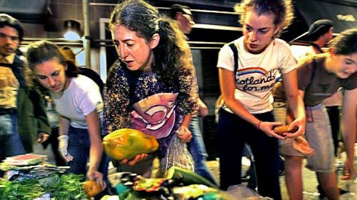 Janet Kalish, center, with a papaya she collected during a New York City trash tour for people interested in becoming freegans -- anti-consumerists who, in the words of one advocate, are "opting out of capitalism in any way that we can."