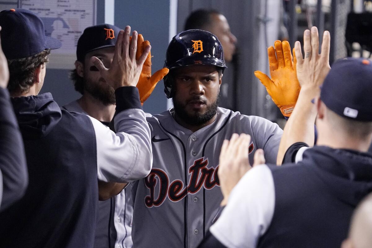 Detroit Tigers' Jeimer Candelario is congratulated by teammates in the dugout after scoring on a double by Javier Baez.