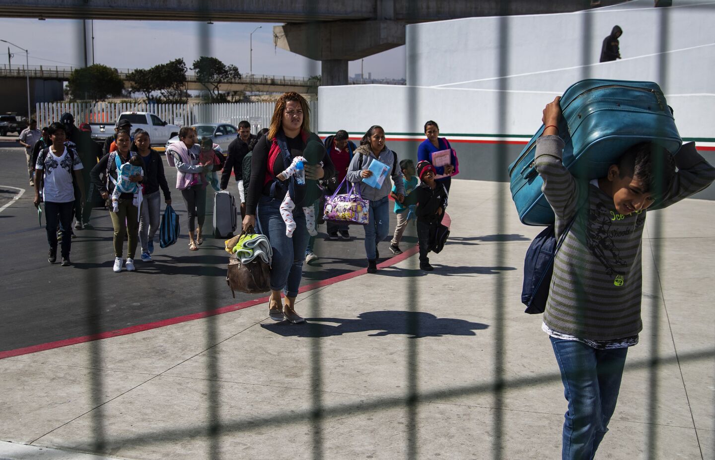 Asylum seekers carry their luggage and hold onto small children as they head to the U.S. border were they will be directed to a holding area to be processed by U.S. Border and Customs Protection in Tijuana, Mexico.