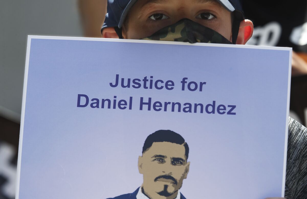 Matthew Hernandez, 8, holds a sign with a picture of his uncle, Daniel Hernandez, who was fatally shot by an LAPD officer.
