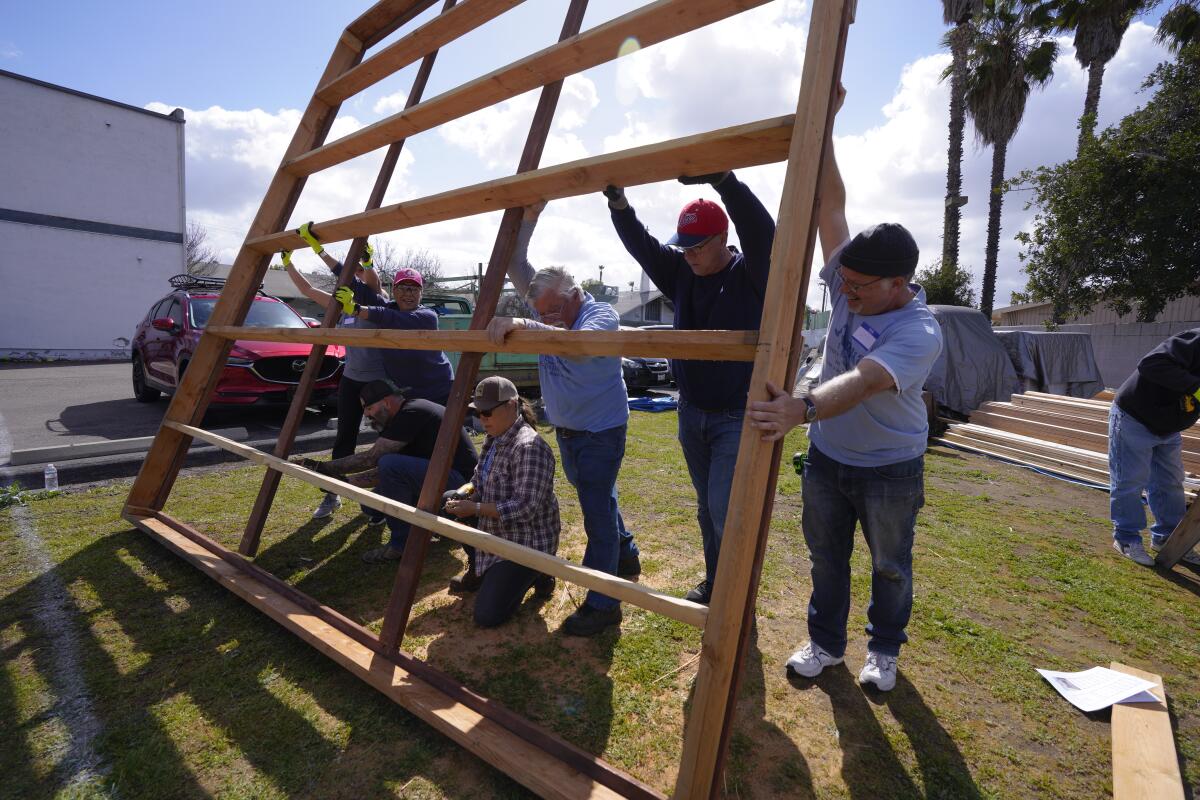 People raise a wood frame for constructing a small cabin