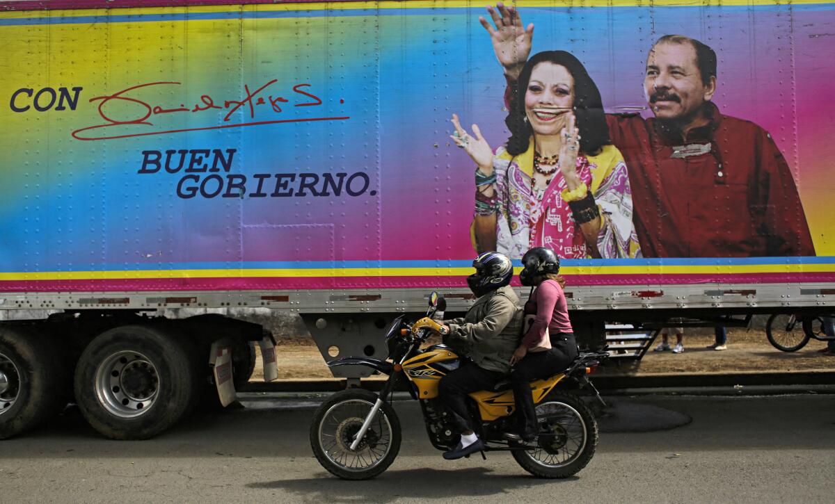 A motorcyclist rides past a banner of Daniel Ortega and his wife.