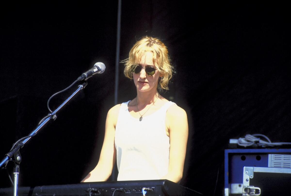 A woman in a rock band playing keyboards onstage