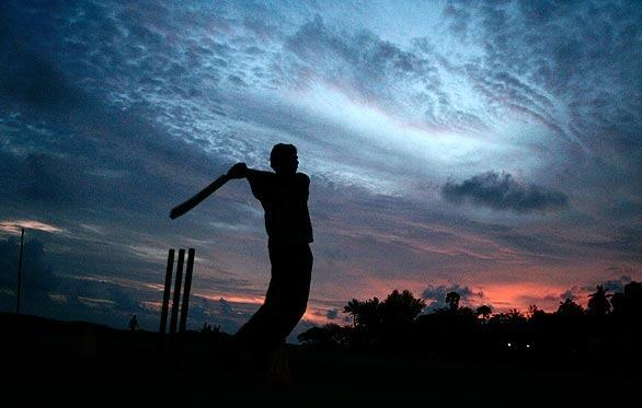 A Sri Lankan boy plays cricket by the sea.