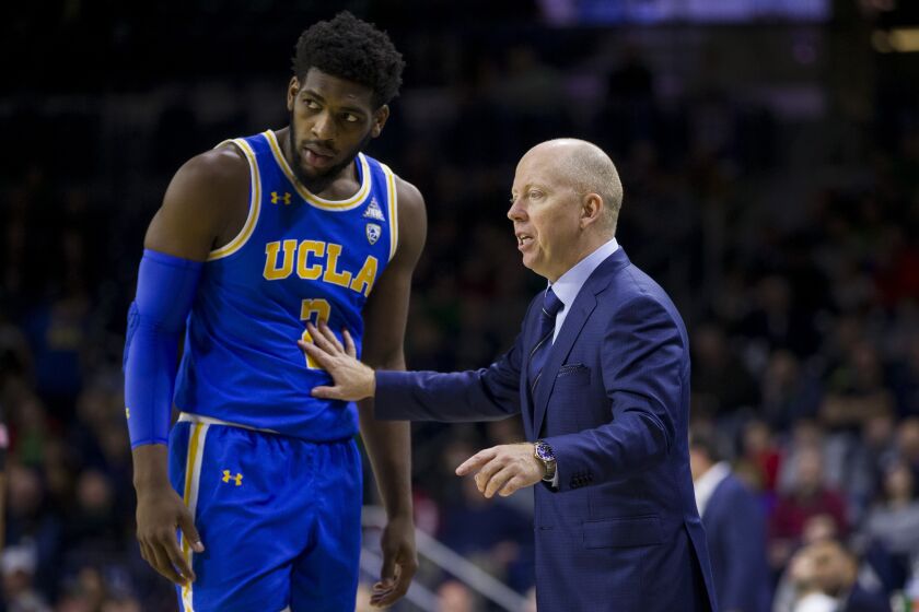UCLA head coach Mick Cronin talks to player Cody Riley (2) during an NCAA college basketball game.