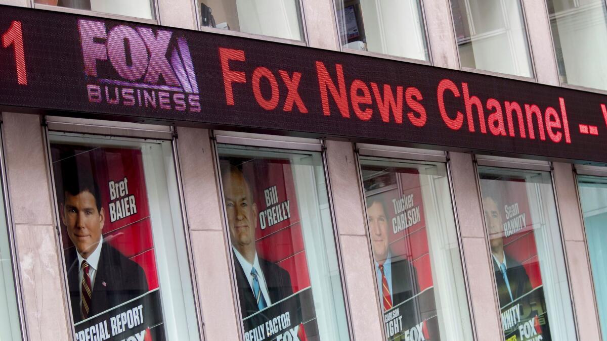 Posters featuring Fox News hosts, including one of Bill O'Reilly, are displayed at News Corp. headquarters in New York. O'Reilly was recently ousted from Fox News after reports of sexual harassment settlements.