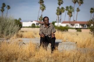 Palm Springs, CA - May 28: Alvin Taylor sits on a remaining foundation of a home in Section 14, as he and his wife Delia Ruiz visit an are in Palm Springs where their family's homes was seized on Tuesday, May 28, 2024 in Palm Springs, CA. (Jason Armond / Los Angeles Times)