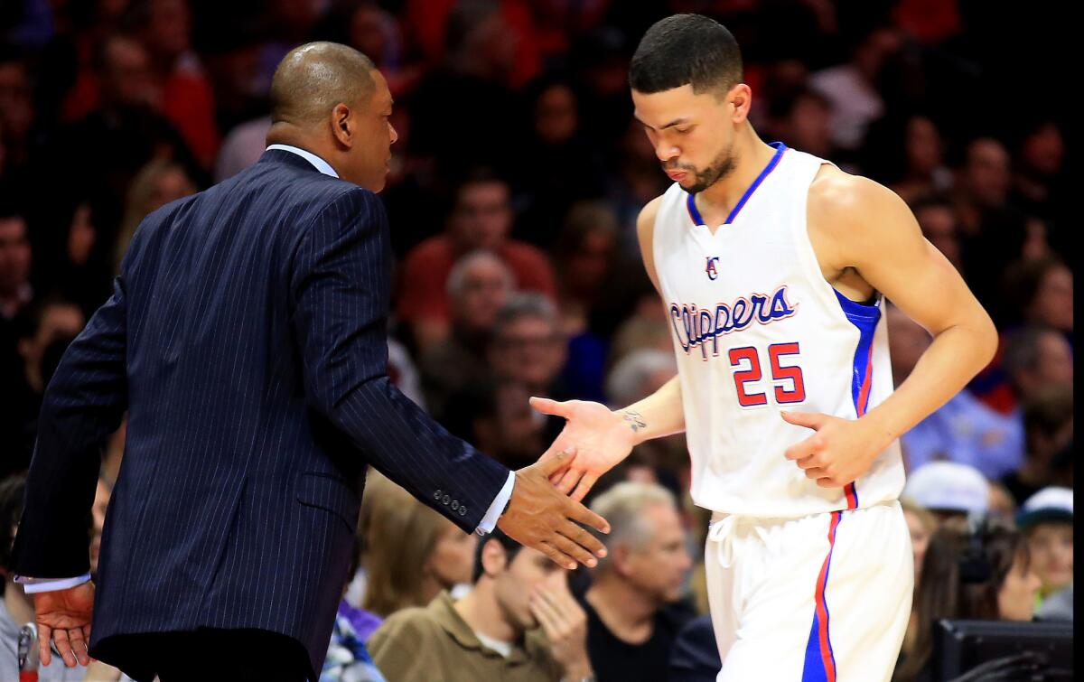 Clippers Coach Doc Rivers slaps hands with his son, newly acquired guard Austin Rivers, as he leaves the game against the Cleveland Cavaliers in the first half Friday night.