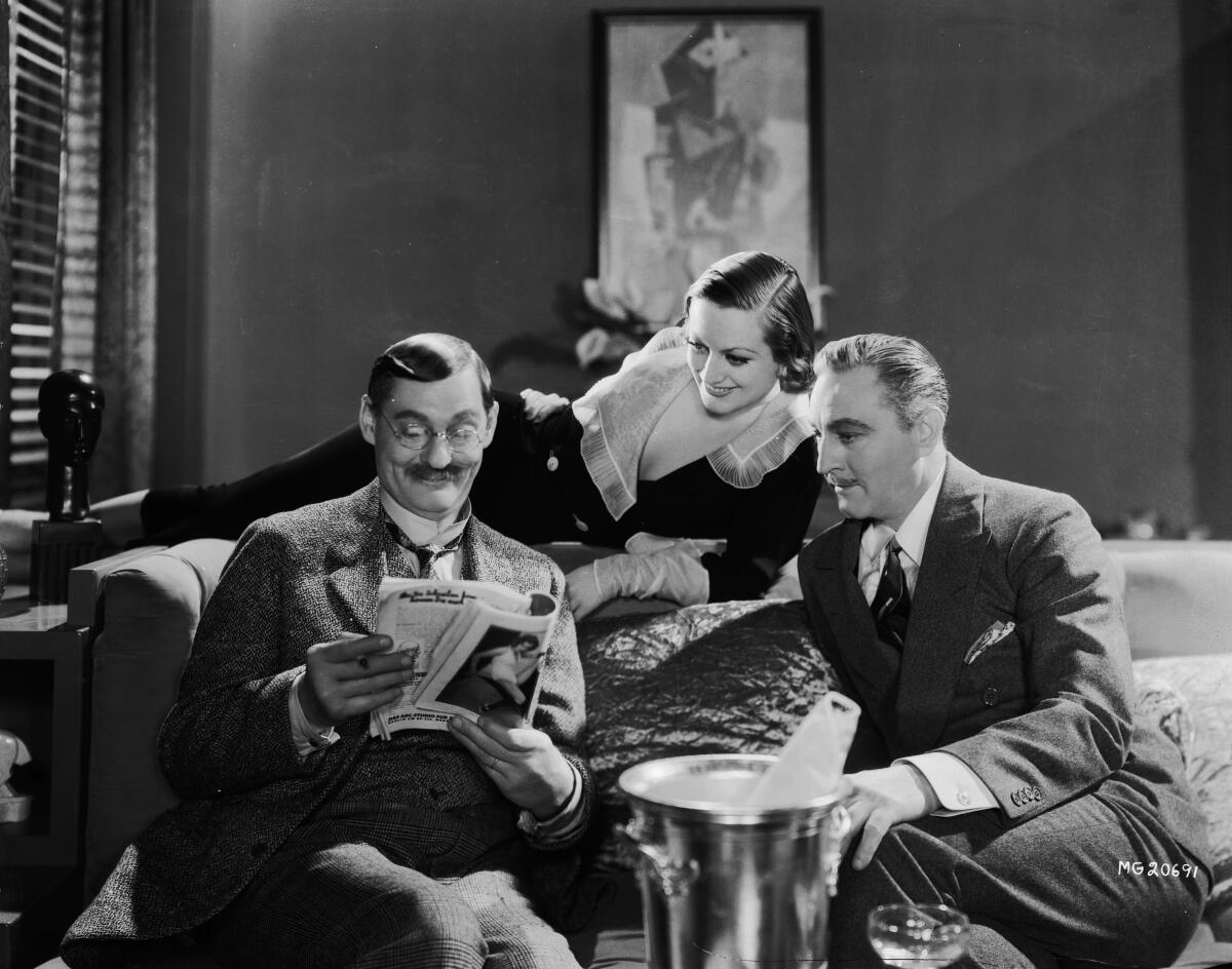  John Barrymore, left, reads a magazine while sitting on a bed with Joan Crawford  and Lionel Barrymore.