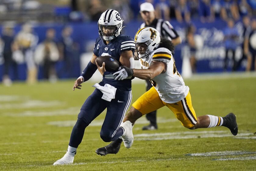 BYU quarterback Jaren Hall carries the ball past Wyoming linebacker Shae Suiaunoa during the first half of an NCAA college football game Saturday, Sept. 24, 2022, in Provo, Utah. (AP Photo/Rick Bowmer)