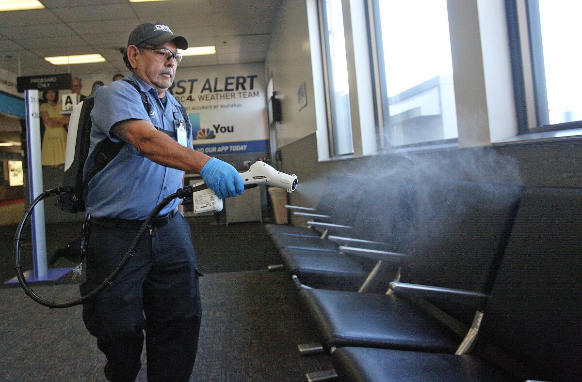 Inside Hollywood Burbank Airport, Isidro Vaca, with Diverse Facility Solutions, sanitizes a waiting area with a Protexus electrostatic backpack sprayer on Friday. The airport is stepping up its sanitation practices to protect passengers from the spread of the coronavirus.