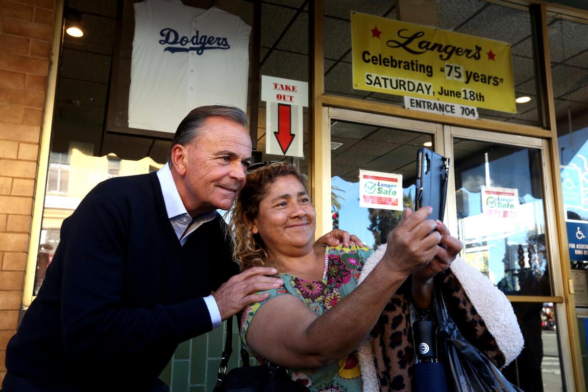 Mayoral candidate Rick Caruso takes a selfie with a supporter.