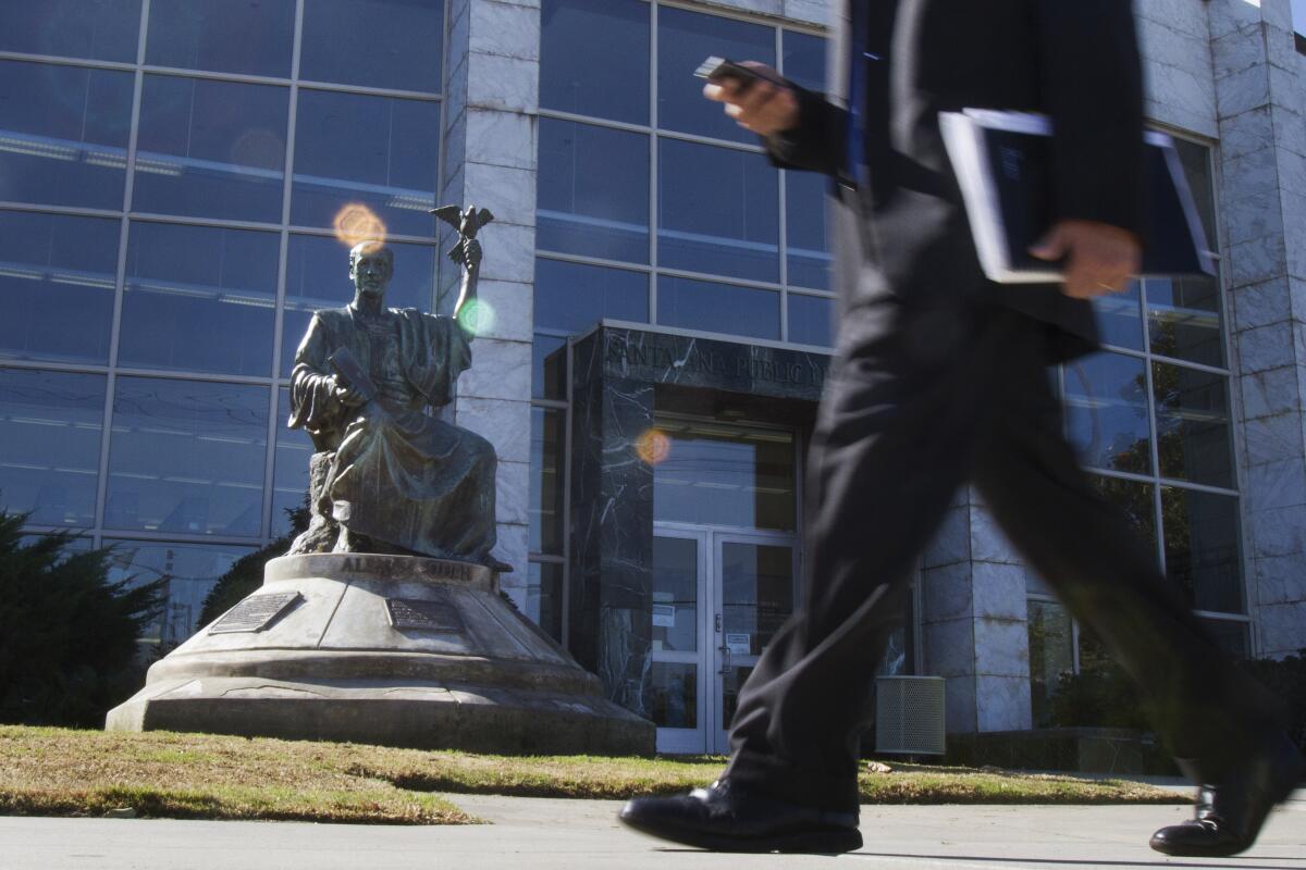 A person in a suit walks past a statue