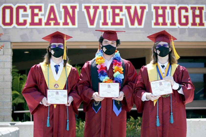 From left, Sean Mosher, Aidan Nguyen and Gavin Mosher pose for a photo with their diplomas after a drive-thru graduation at Ocean View High School, in Huntington Beach on Wednesday, June 10, 2020. More than 280 students drove through the school during the day at a pace of about 50 an hour.
