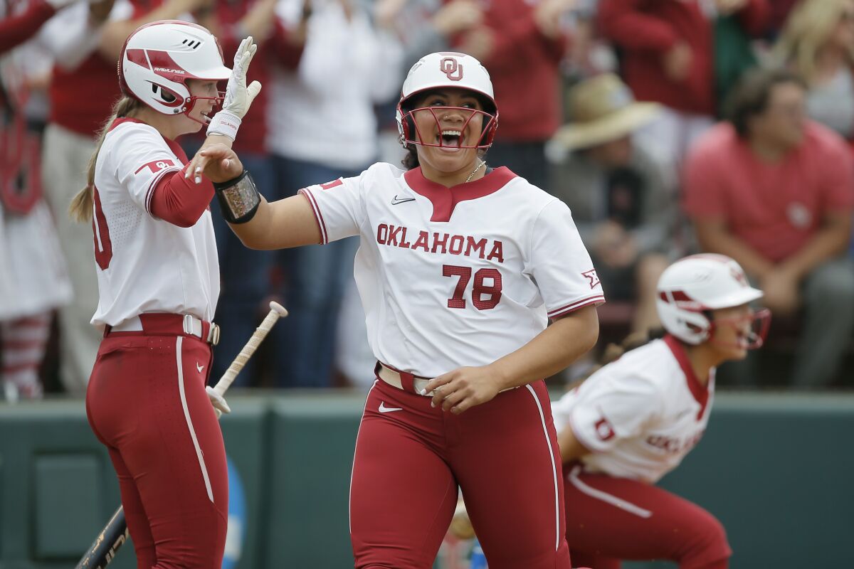 Oklahoma's Jocelyn Alo (78) celebrates with Jana Johns (20) after scoring a run against Texas A&M in the first inning of a softball game in the NCAA Norman Regional in Norman, Okla., Sunday, May 22, 2022. (Bryan Terry/The Oklahoman via AP)