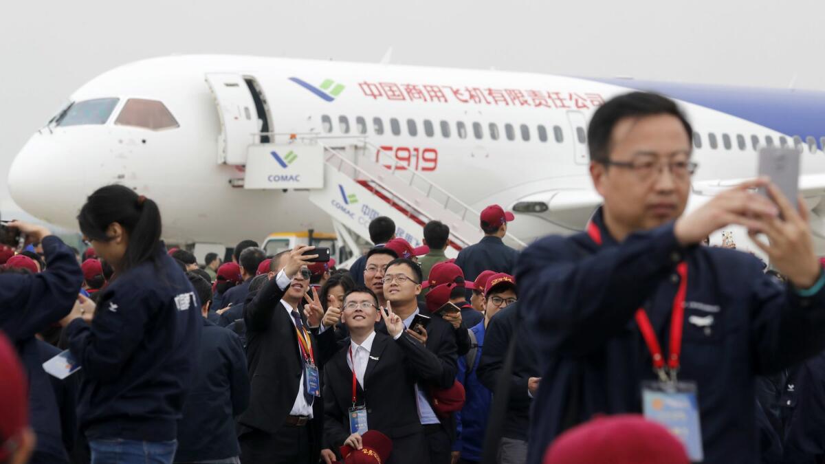 Attendees take photos in front of a Chinese C919 passenger jet after its first flight at Shanghai's Pudong International Airport in 2017.