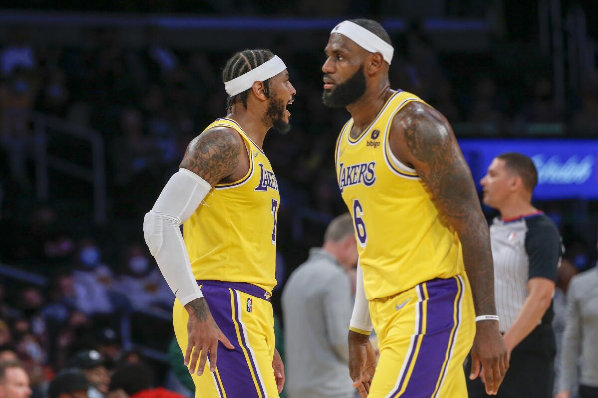 Lakers forward Carmelo Anthony reacts in front of LeBron James during a preseason game against the Warriors.