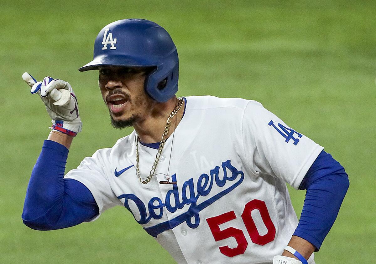 Dodgers right fielder Mookie Betts leans and gestures with his fingers toward his teammates