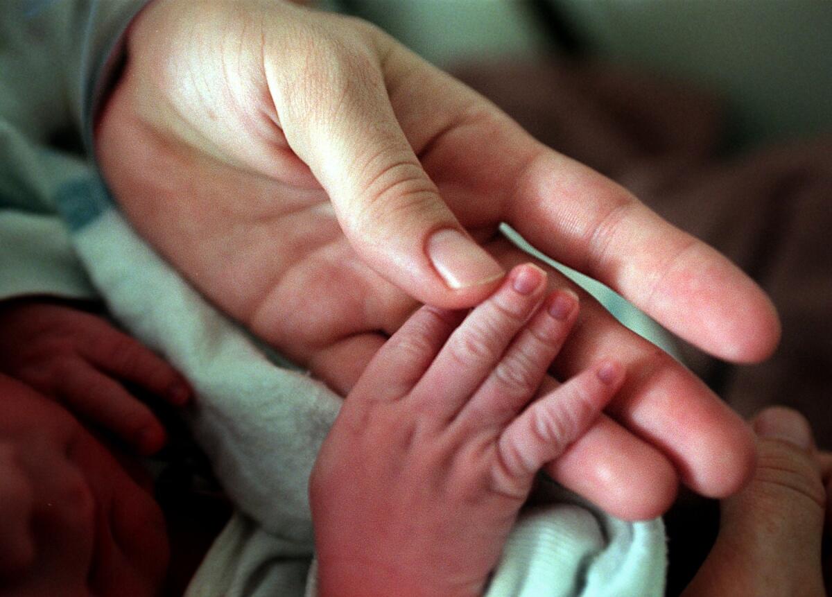 Mother holds infant's hand