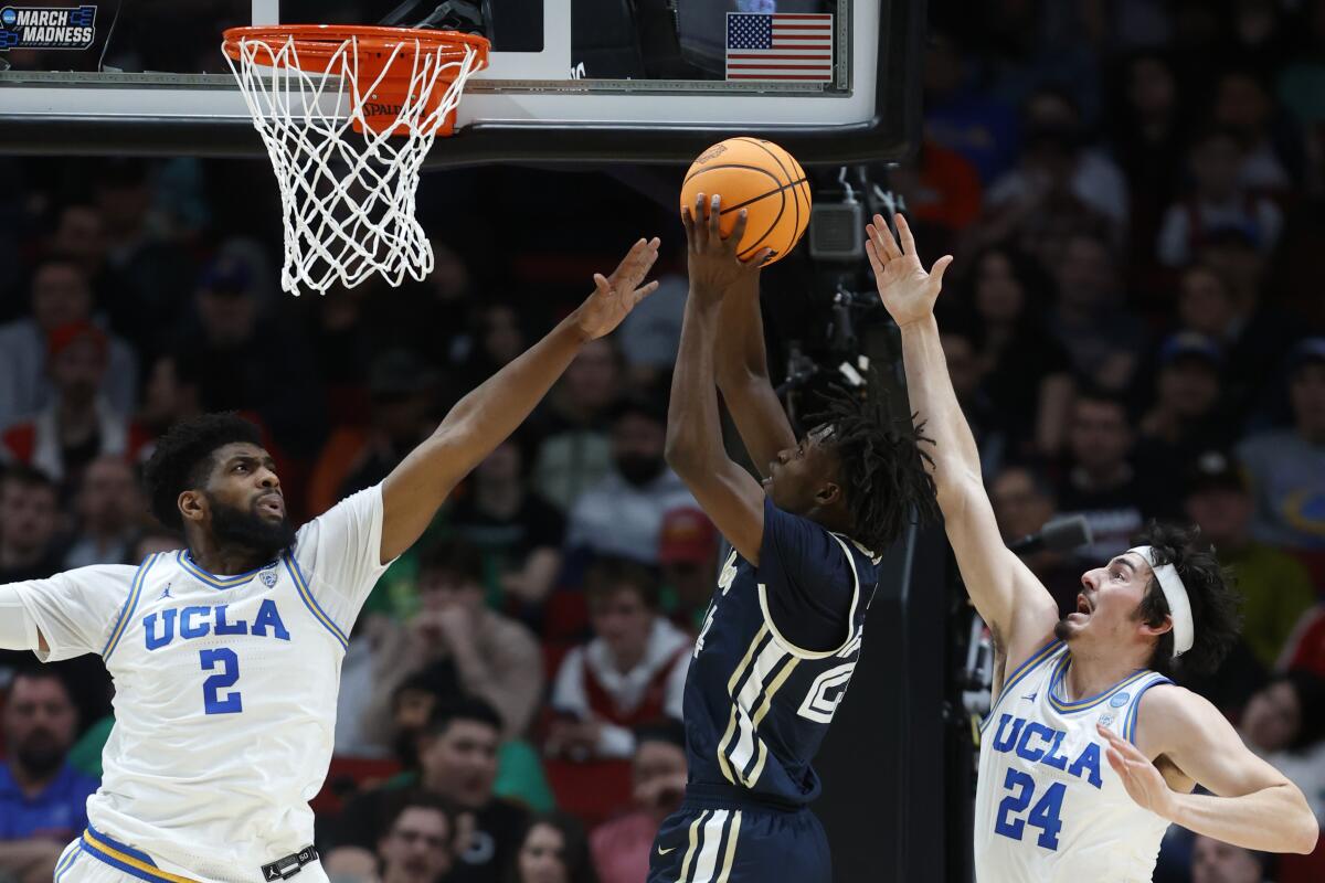 Akron forward Ali Ali goes for a dunk as UCLA forward Cody Riley and guard Jaime Jaquez Jr. defend.