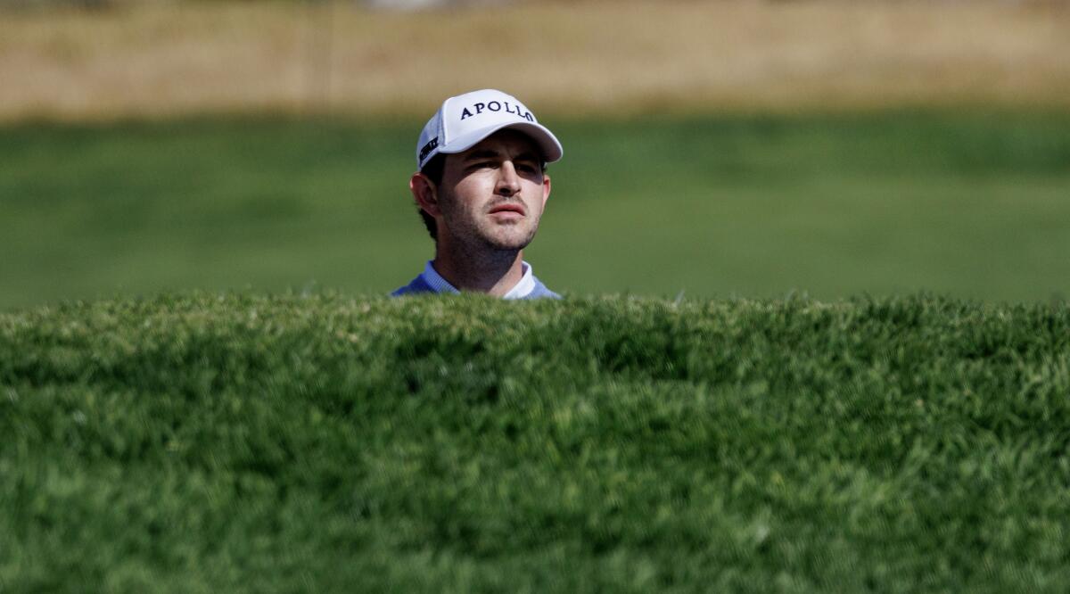 Patrick Cantlay peers over the ledge of a green side bunker on 14th hole during the first round of the Genesis Invitational.