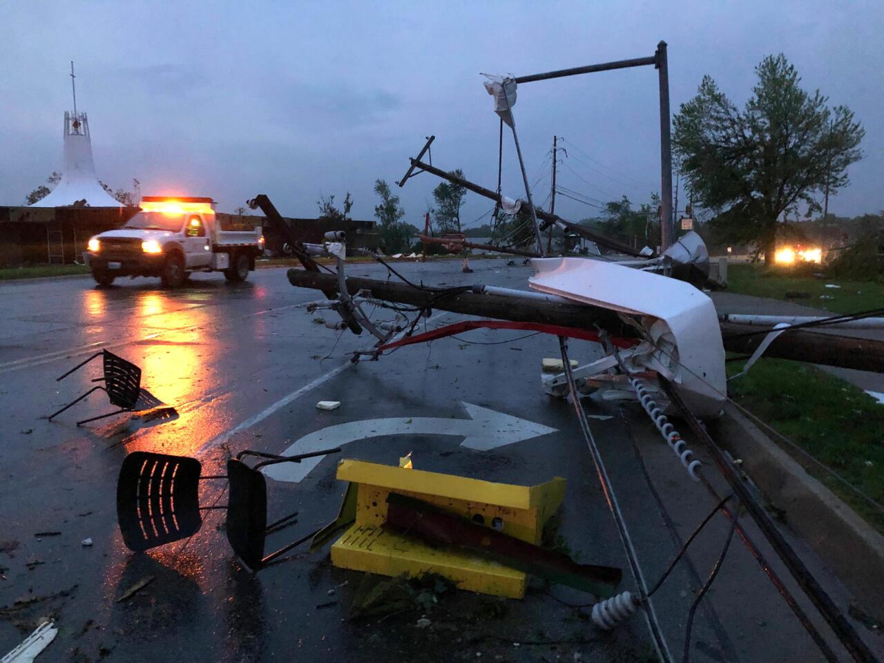 Metal from a damaged gas station roof is twisted around a downed power line in Jefferson City, Mo.