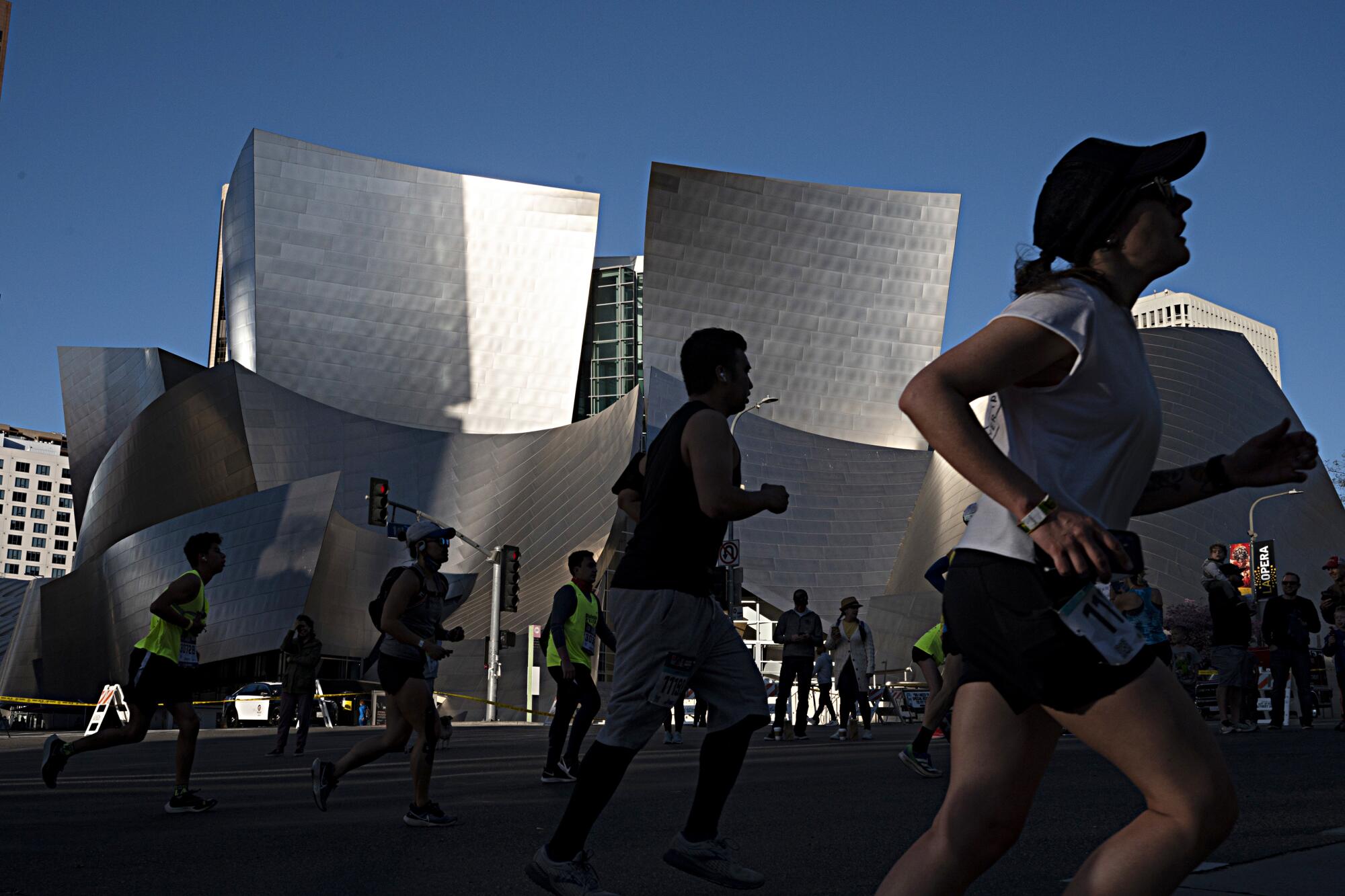 Runners pass Walt Disney Concert Hall.