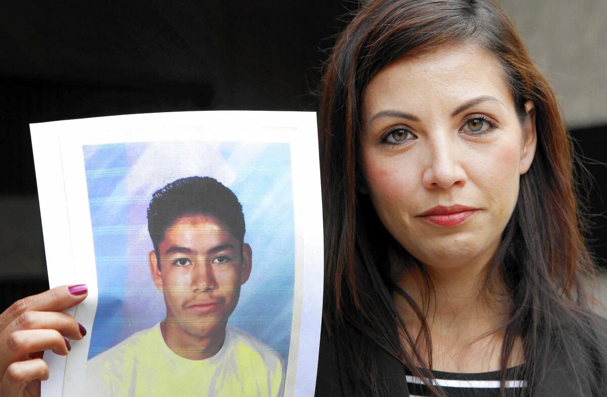 Lydia Espinoza Oregel, at a 2013 news conference, shows a photo of her brother Edel Gonzalez when he was 16.