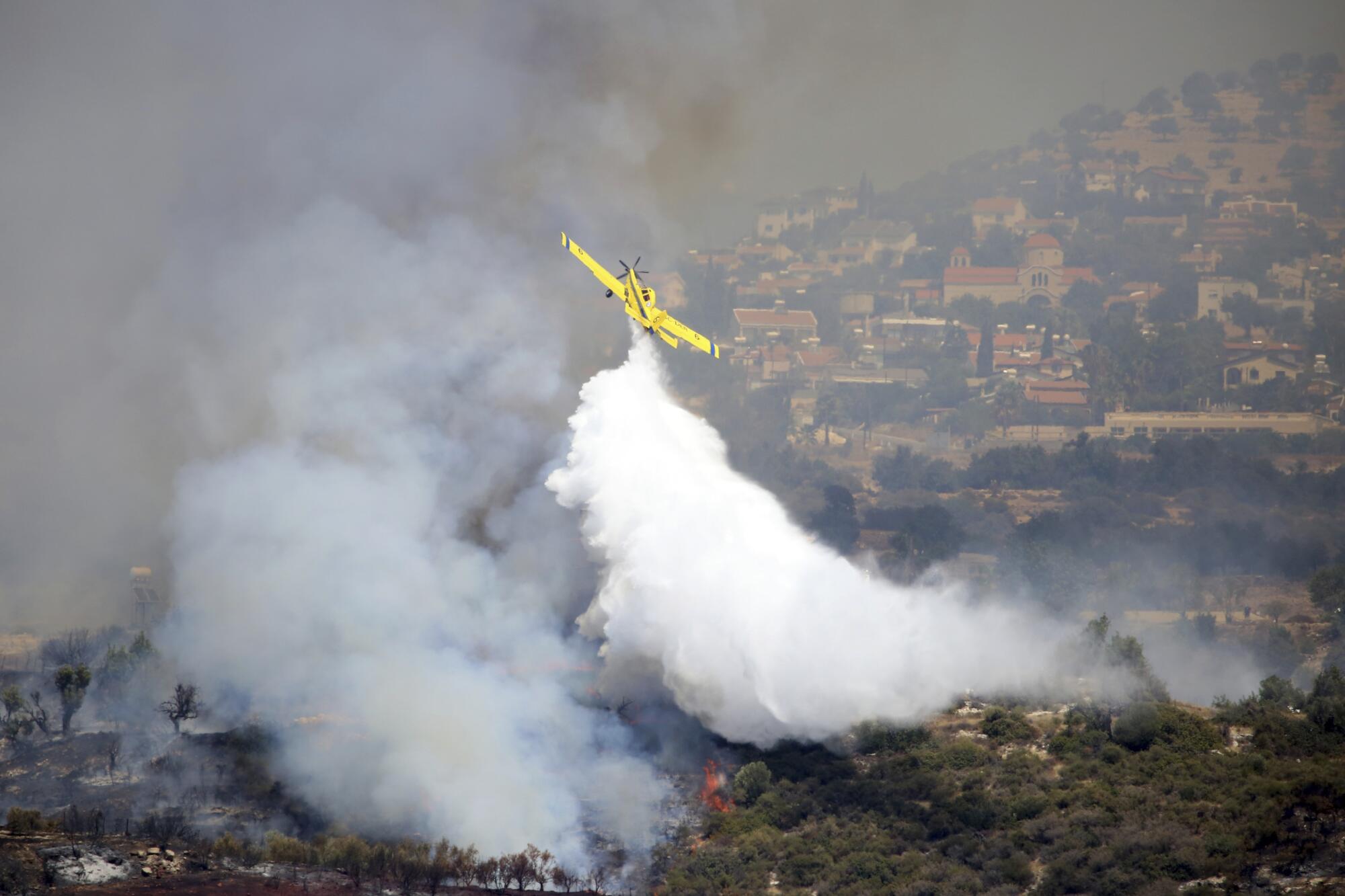 An aircraft drops water over a fire in Apesia, a semi-mountainous village near Limassol, southwestern Cyprus.