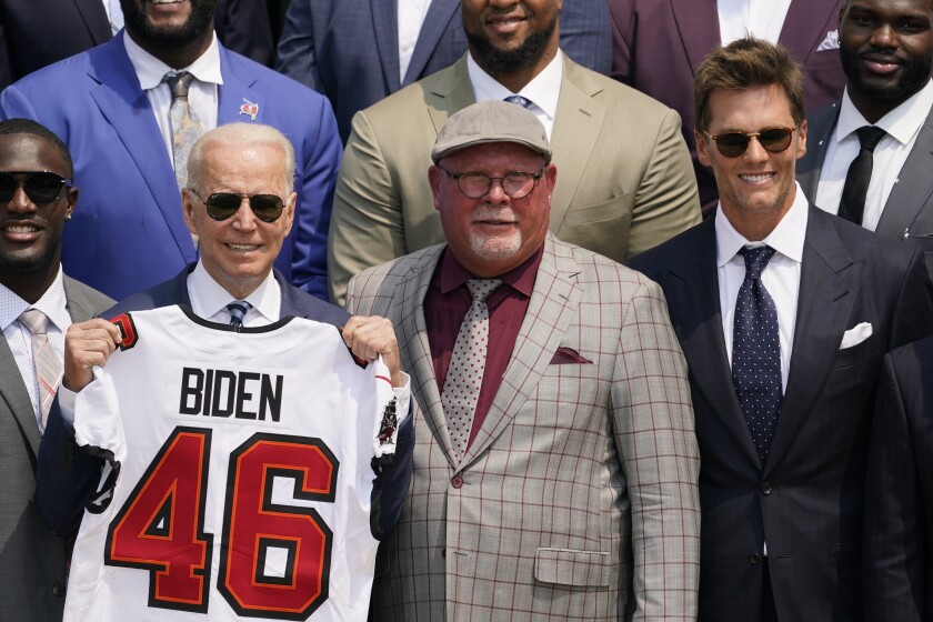 President Joe Biden, surrounded by members of the Tampa Bay Buccaneers, poses for a photo holding a jersey during a ceremony on the South Lawn of the White House, in Washington, Tuesday, July 20, 2021, where Biden honored the Super Bowl Champion Tampa Bay Buccaneers for their Super Bowl LV victory. Tampa Bay Buccaneers quarterback Tom Brady, right, and Tampa Bay Buccaneers head coach Bruce Arians look on. (AP Photo/Andrew Harnik)