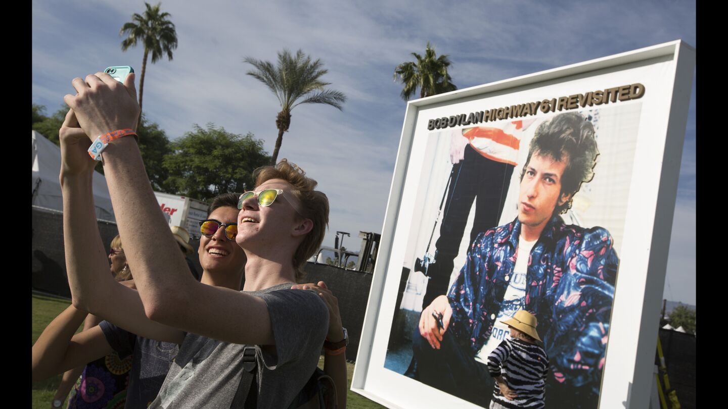 Antonio Villa, left, and Cayden Himes, 18, of Prescott, Ariz., take a photo with a Bob Dylan album cover poster.