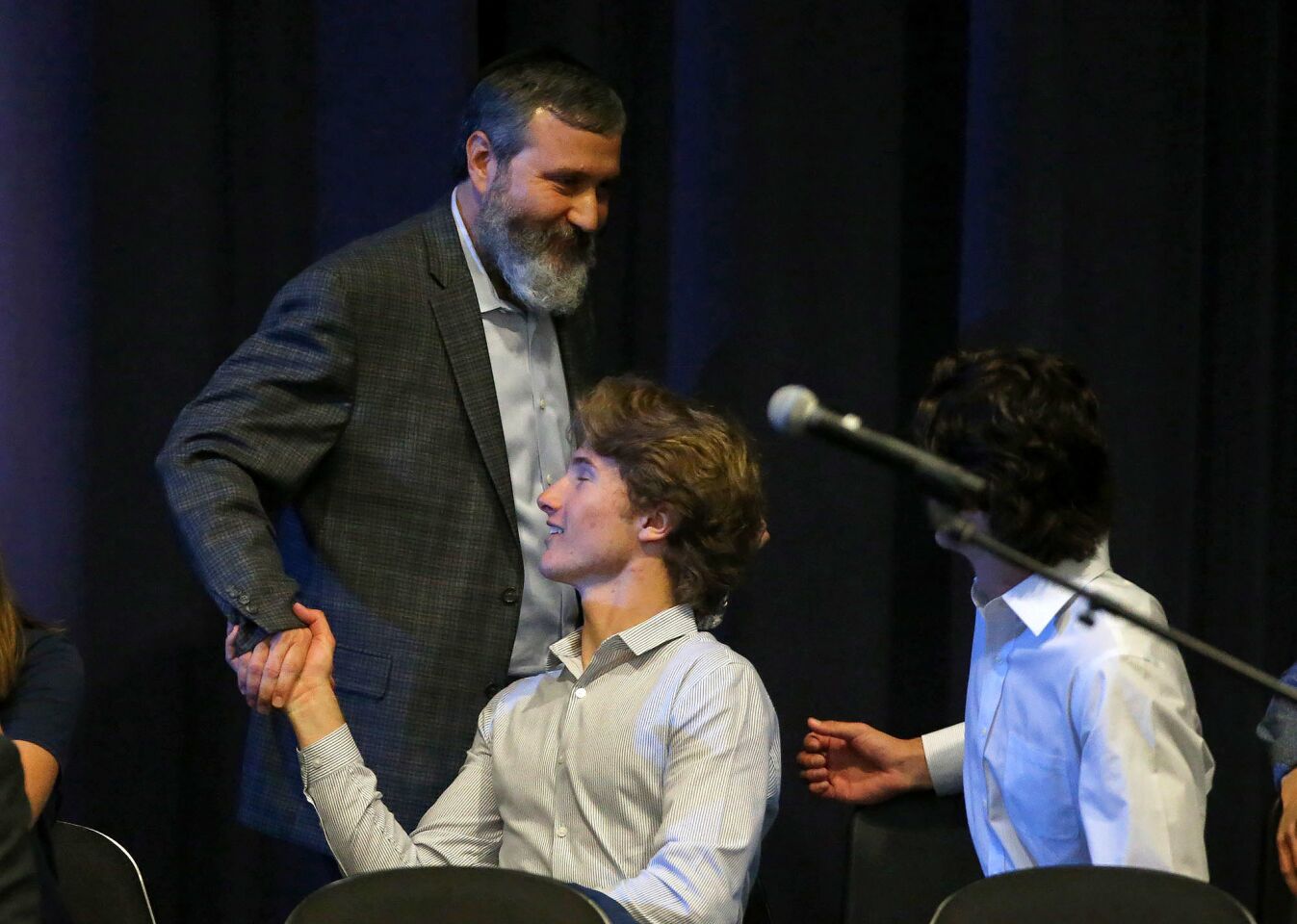 Rabbi Reuven Mintz of the Chabad Center for Jewish Life shakes hands with Newport Harbor High School Associated Student Body President Jack Rogers during a town hall-style meeting Monday night at the school to discuss an off-campus weekend party where students were pictured saluting a swastika made of red cups during a drinking game.