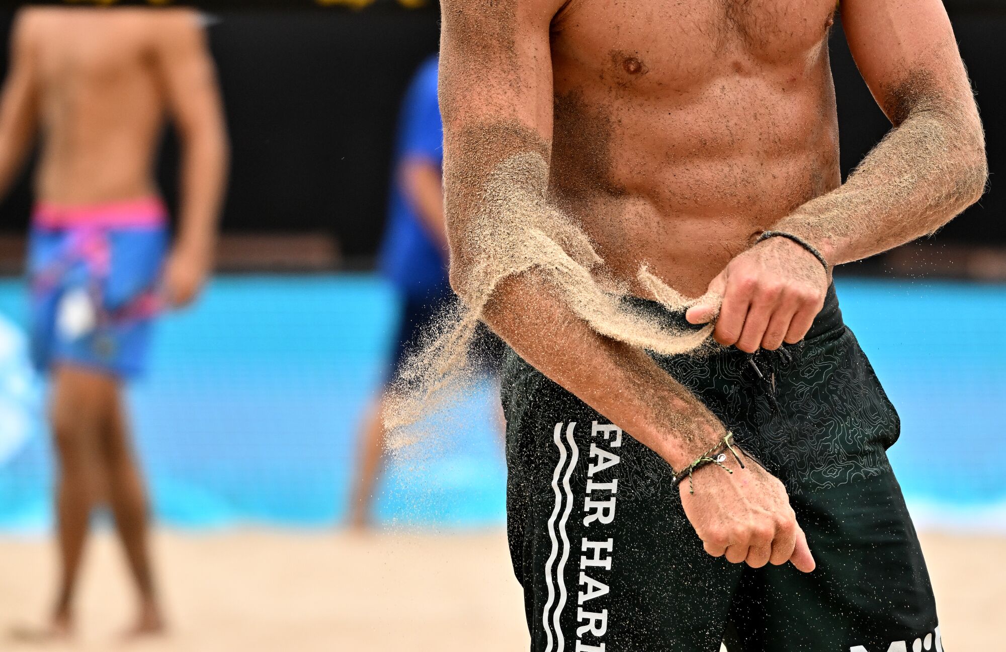 Jeremy Casebeer rubs sand on his arms during a quarterfinal match.