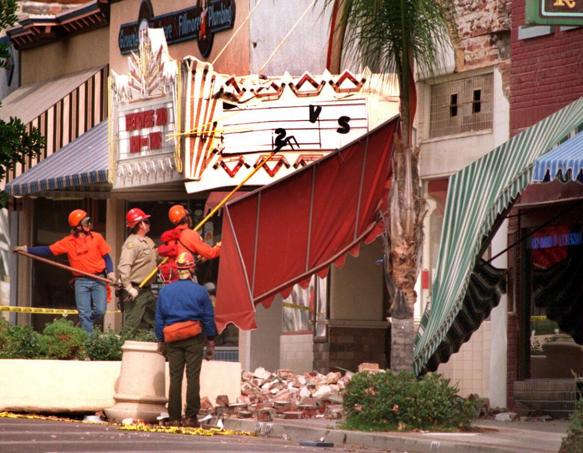 Workers remove awnings and debris hanging from the area of the Theatre in Fillmore.